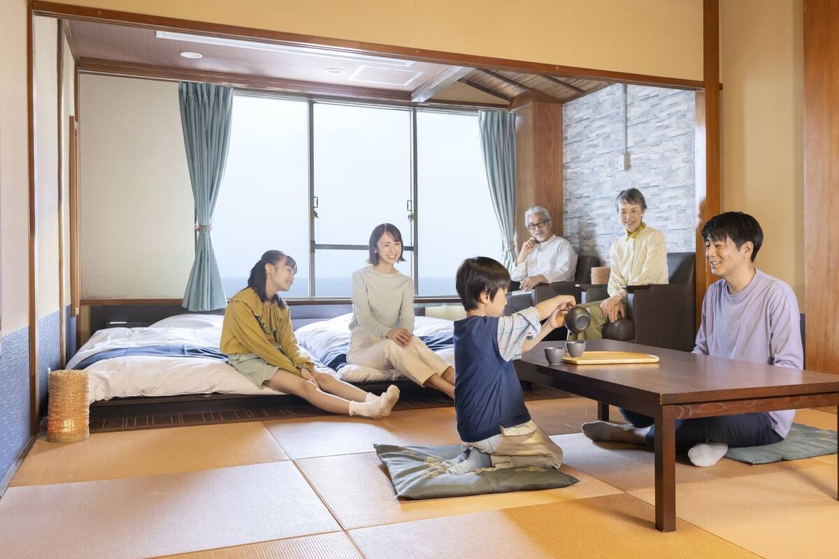 A tatami mat room with a low table, a sofa, and a window with curtains.