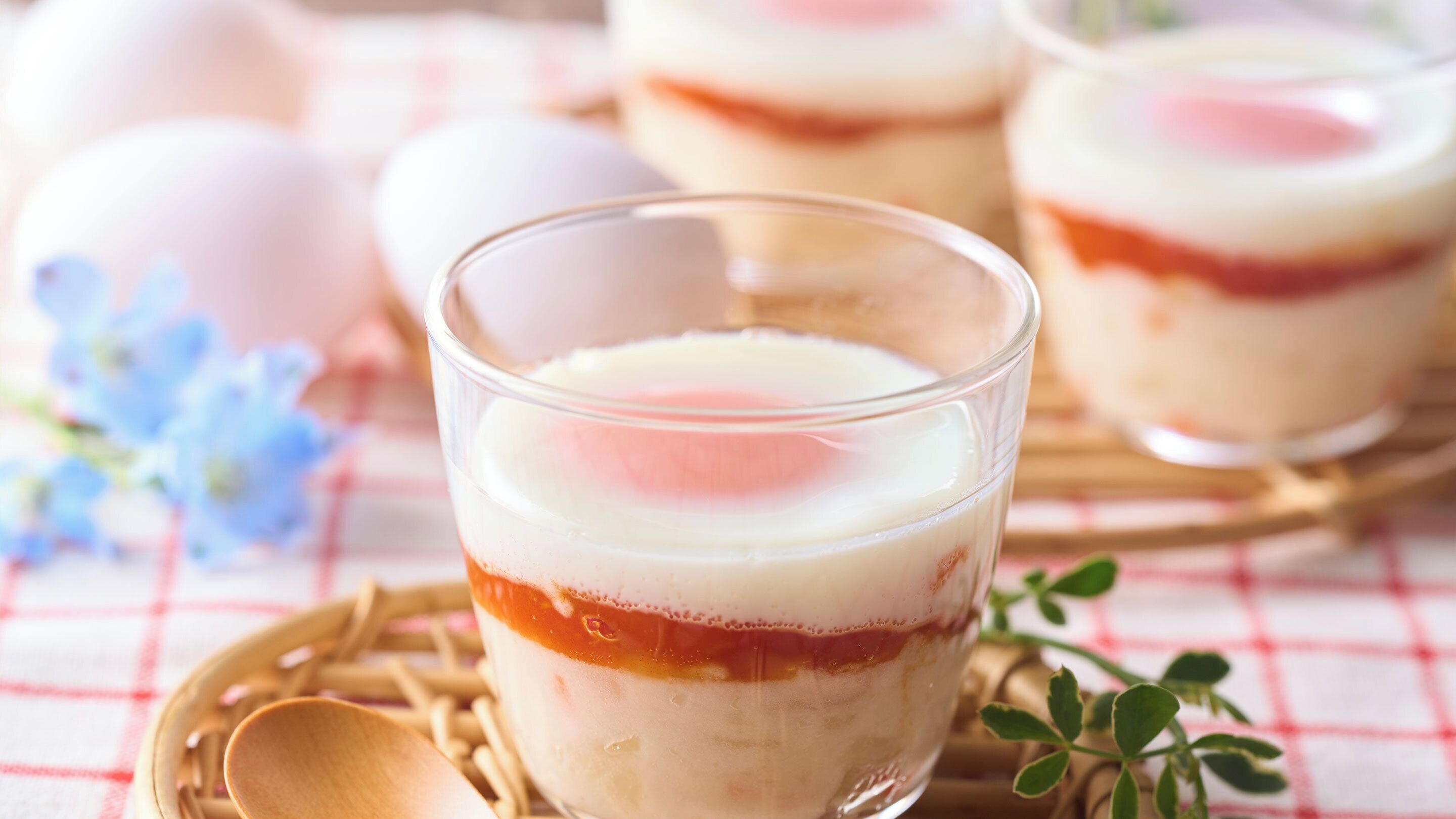 Postre de vidre amb capes de farciment i una culleradeta de nata a sobre, damunt una tovallola escachenada.