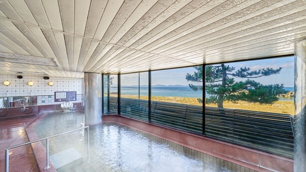 A spacious indoor area with a large window overlooking a beach, a tiled floor, and a ceiling with a unique design. - Ooedo Onsen Monogatari Kaike (Yonago)