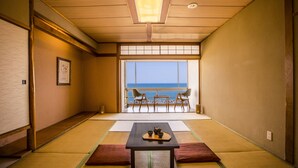 A traditional Japanese room with tatami flooring, a low table with a tea set, and a view of the sea through a large window. - Ooedo Onsen Monogatari Kaike (Yonago)