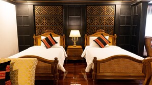A hotel room with two wooden beds, a nightstand with a lamp, and a chair. - Lanna Resort (Hang Dong)