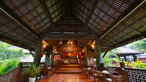 An indoor area with a wooden ceiling, potted plants, and wooden furniture. - Lanna Resort (Hang Dong)