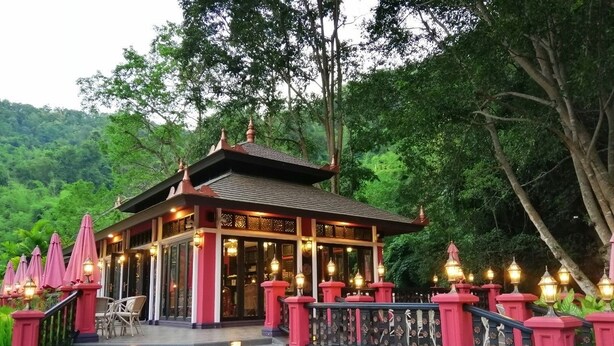 A traditional building with a tiled roof, a staircase leading to the entrance, and a railing with lanterns. - Lanna Resort (Hang Dong)