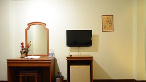 Ett skrivbord i trä med en spegel, en tv och ett litet skåp.