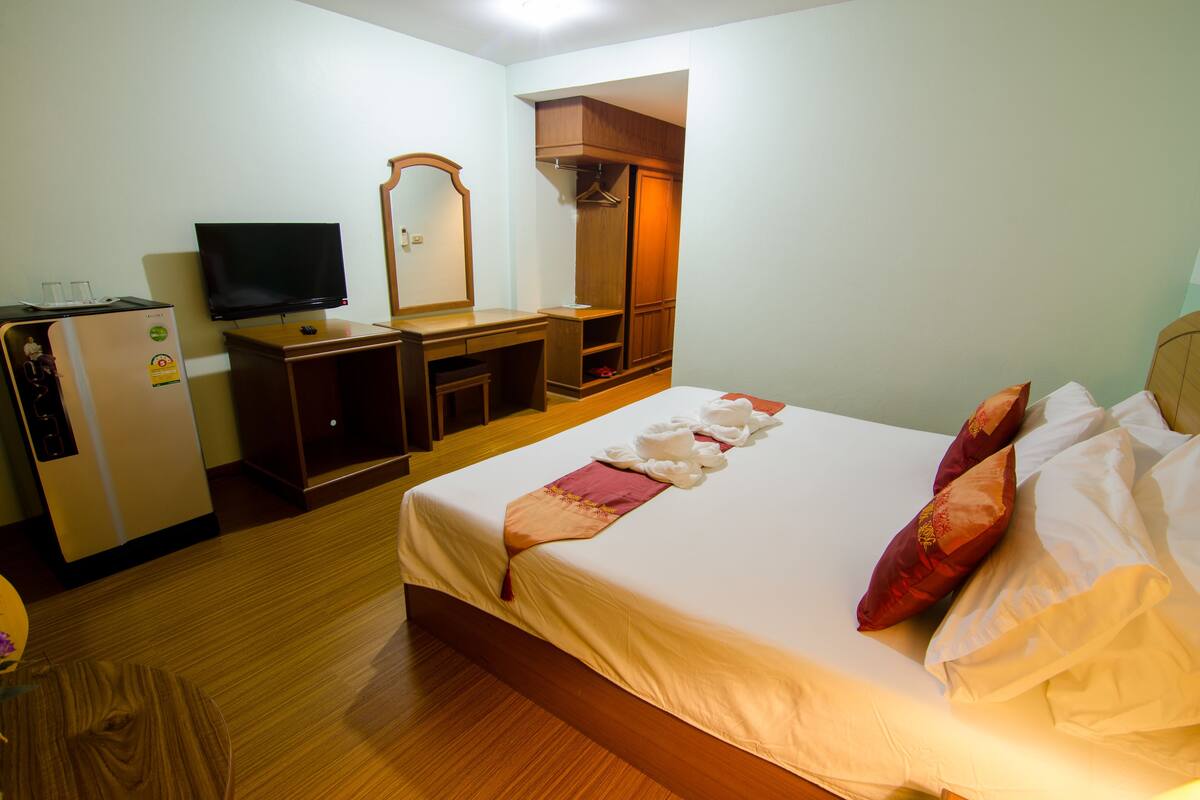 A hotel room with a bed, a TV, a dresser, and a wardrobe.