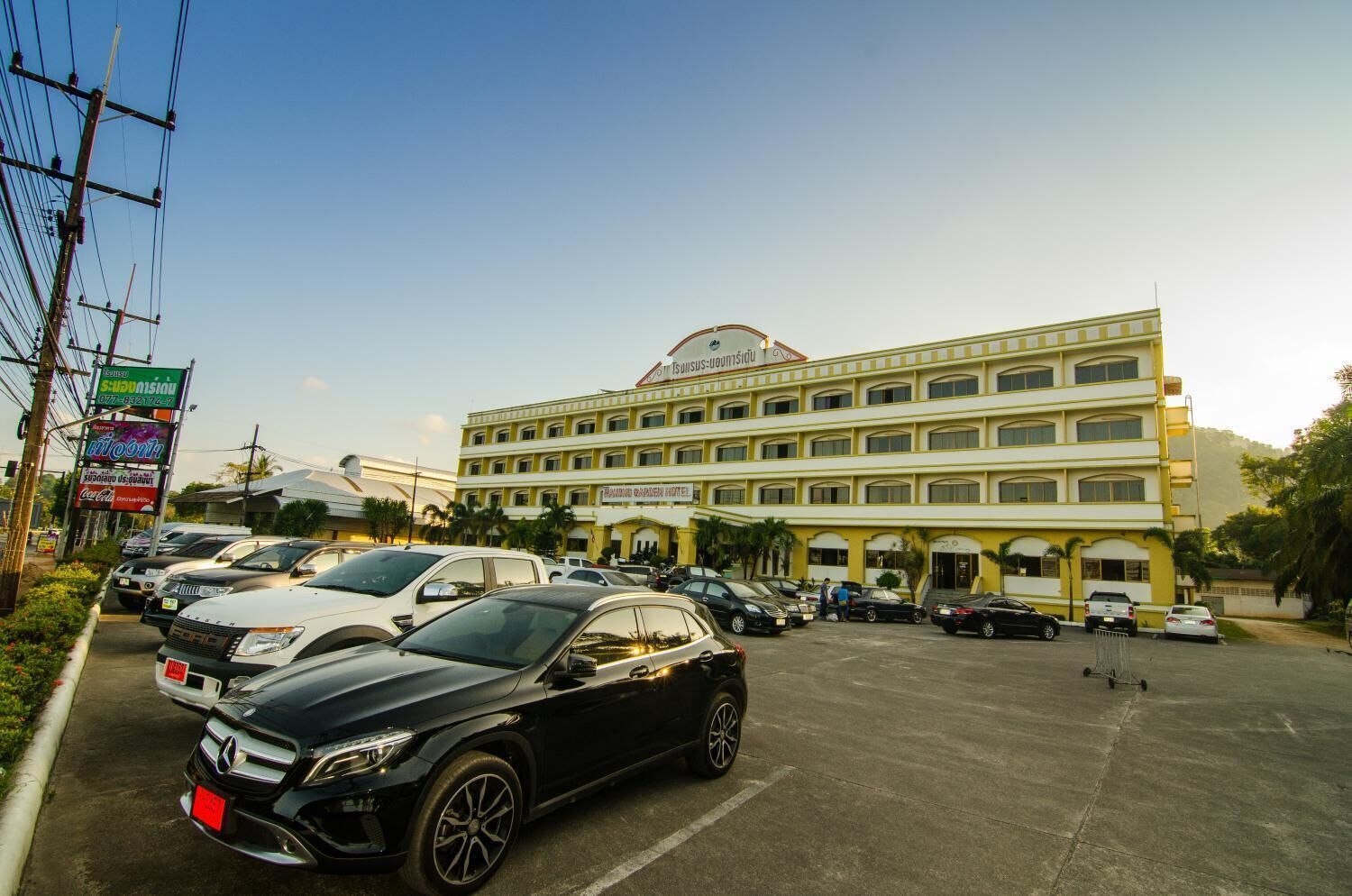 A multi-story hotel with a large parking lot and several cars parked in front.