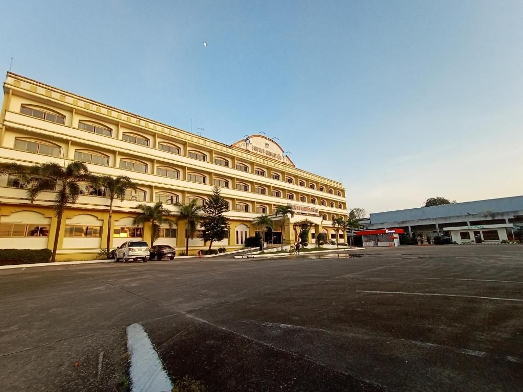 A multi-story hotel with a central courtyard, palm trees, and a parking lot.