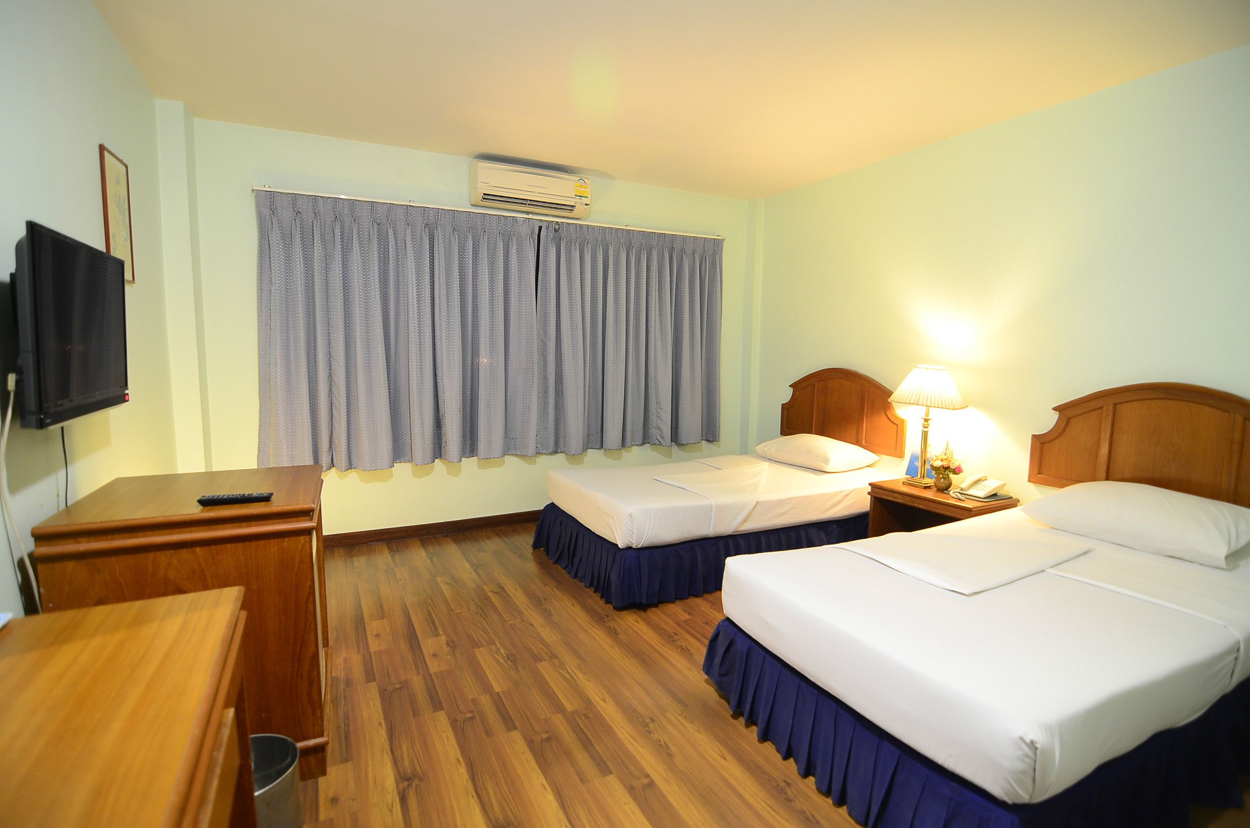 Habitación de hotel con dos camas, un escritorio, un televisor y una ventana con cortinas.