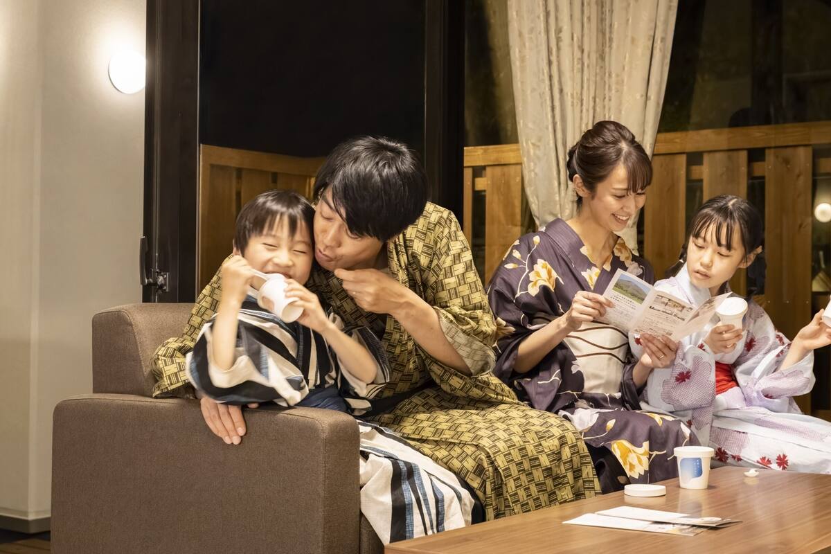 A family sitting on a couch with a table in front of them.