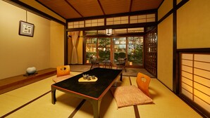 Une pièce de style japonais traditionnel, avec un sol recouvert de tatamis, une petite table sur laquelle est disposé un service à thé, et des portes coulissantes donnant sur un jardin.