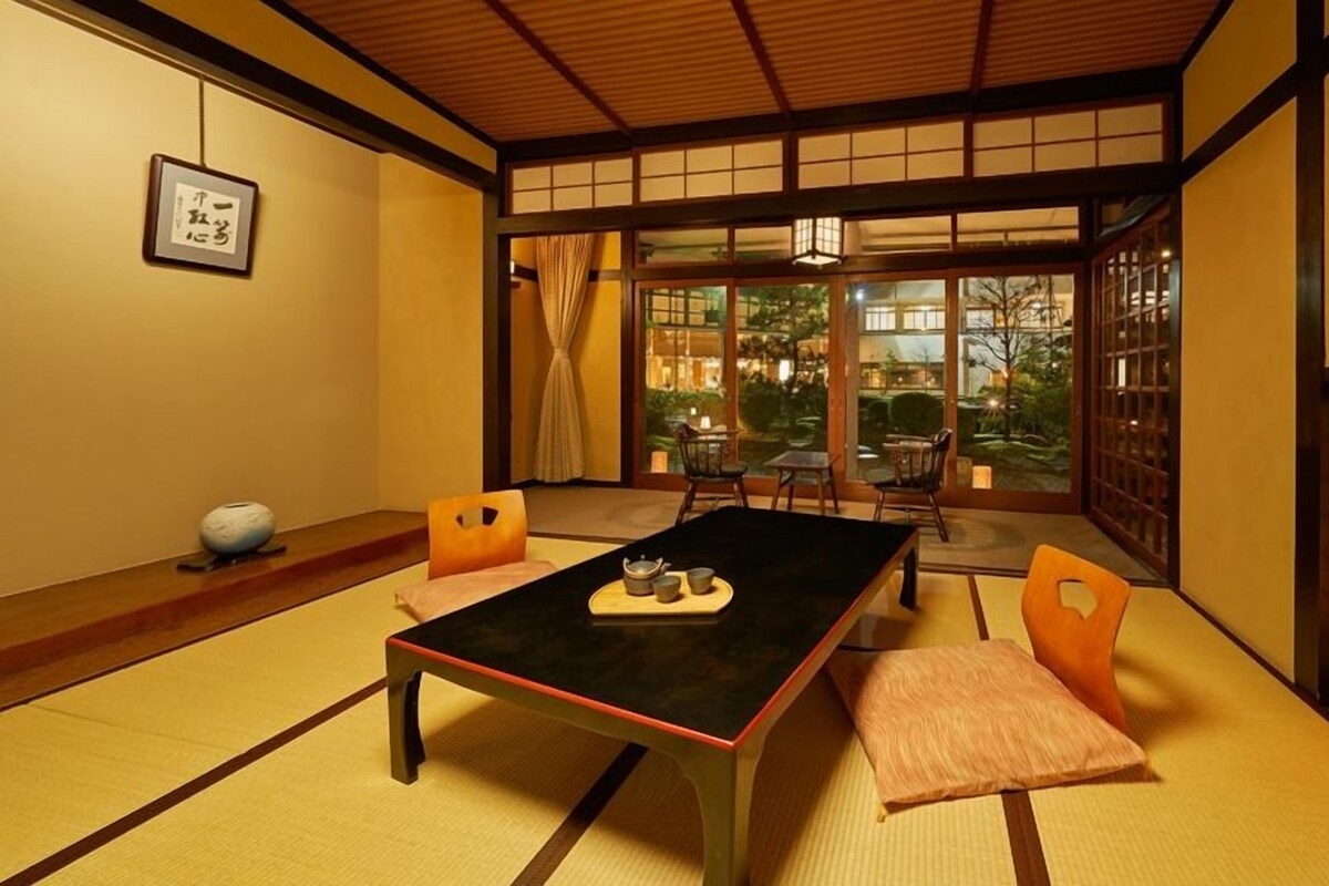 Una habitación tradicional japonesa con suelo de tatami, una mesa baja y puertas correderas.