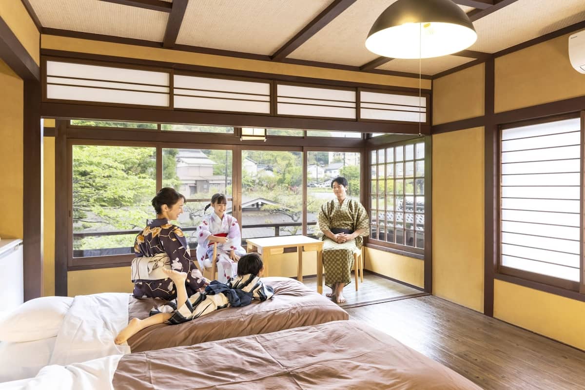 A traditional Japanese room with tatami flooring, a low table, and a large window with a view of greenery.