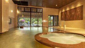 Une piscine intérieure moderne offrant une vue dégagée sur l’extérieur, dotée d’un plancher en bois et d’un mur en verre.