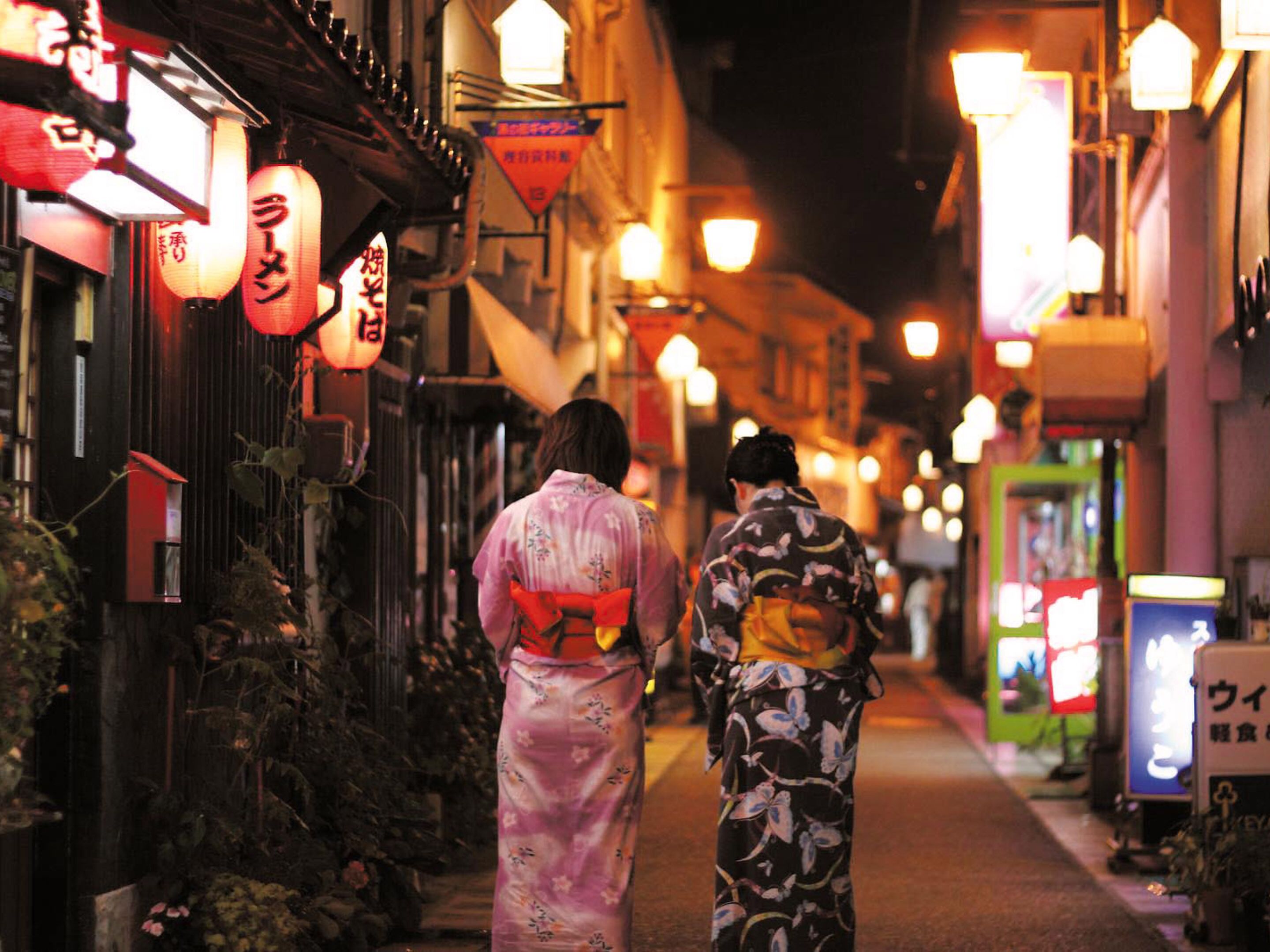 A narrow street lined with traditional buildings and illuminated by hanging lanterns.
