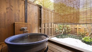 Un espace de détente en bois comprenant un jacuzzi, une porte en bois et un paravent en bambou.