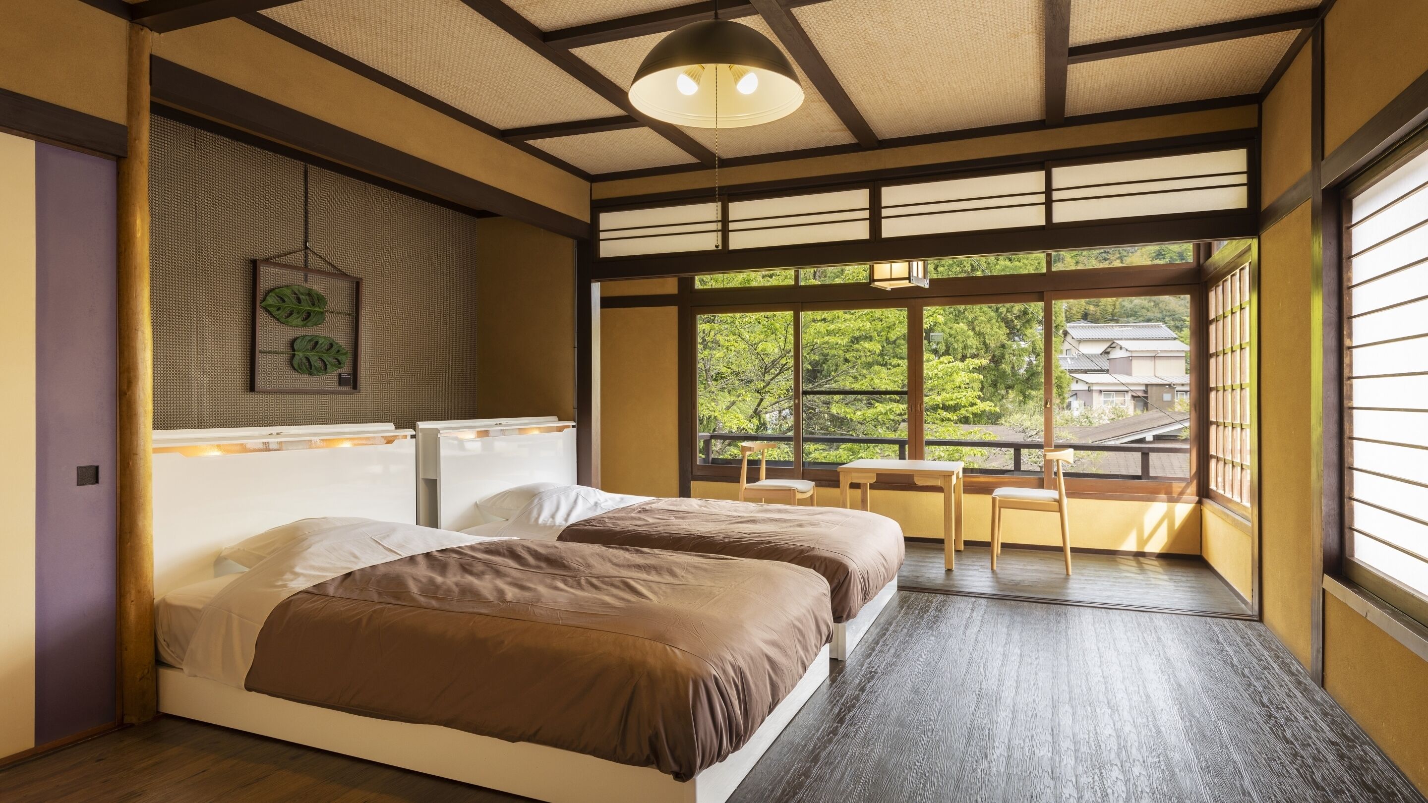 A traditional Japanese-style room with tatami flooring, a bed with brown bedding, a hanging light fixture, and a view of greenery outside.
