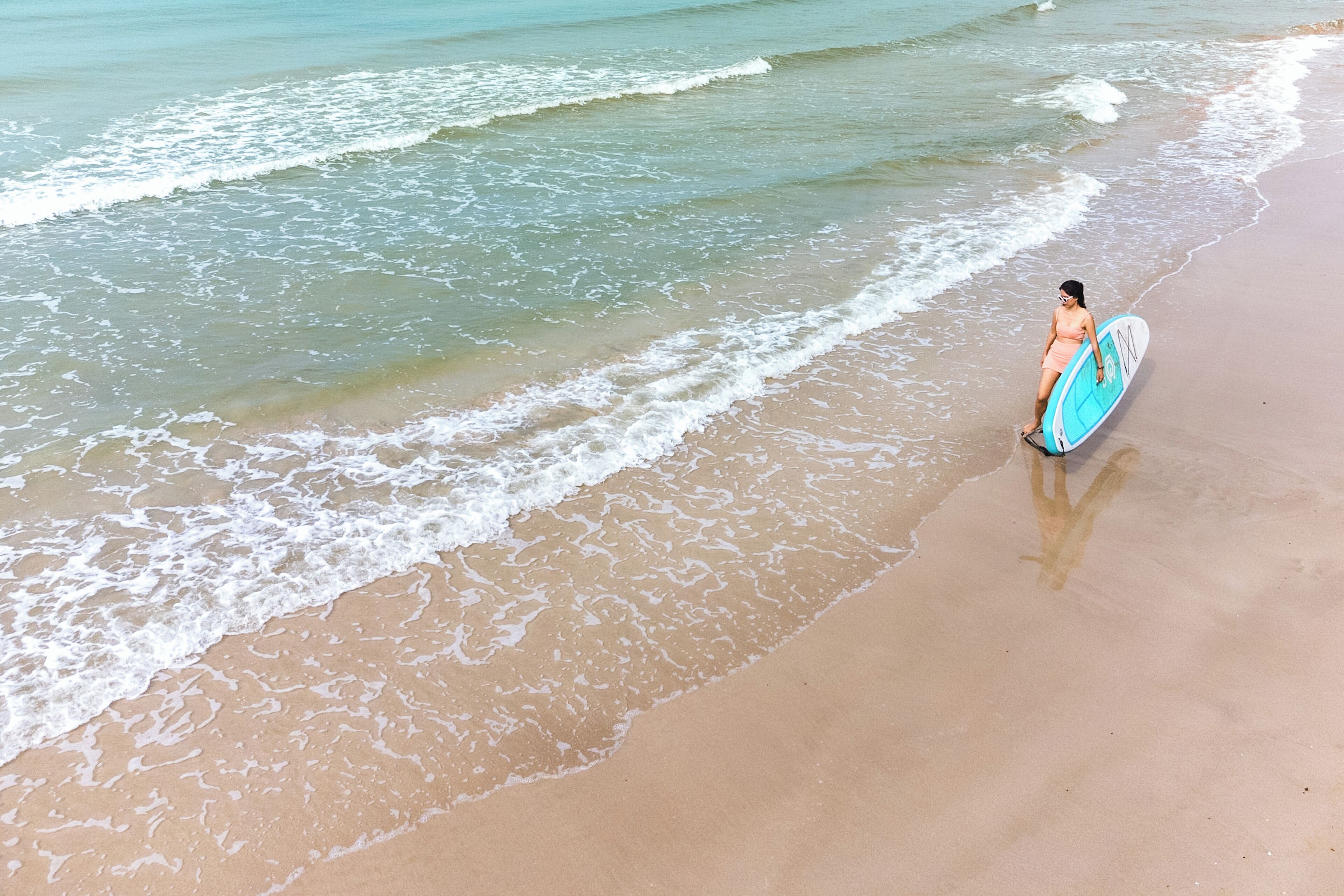 A beach scene with a person carrying a surfboard.