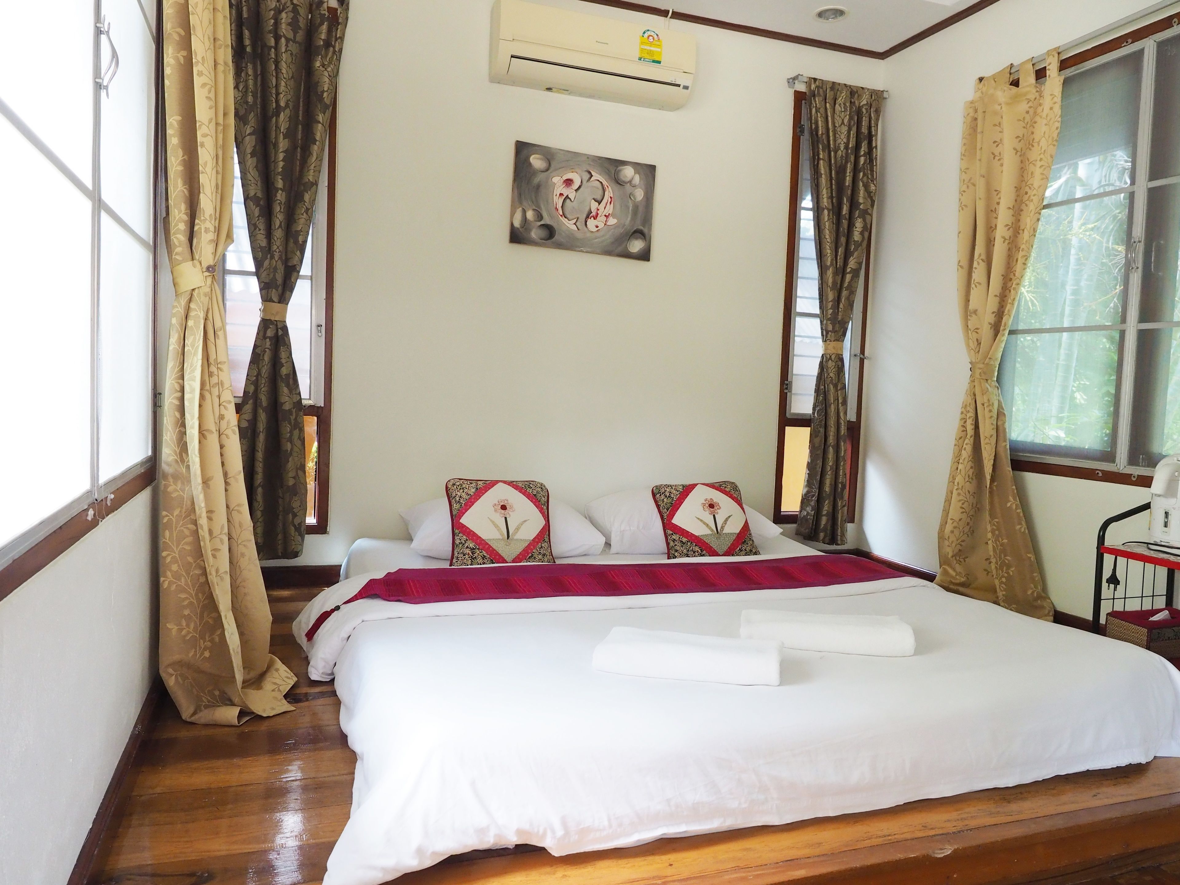 A hotel room with a bed, a painting on the wall, and curtains on the windows.