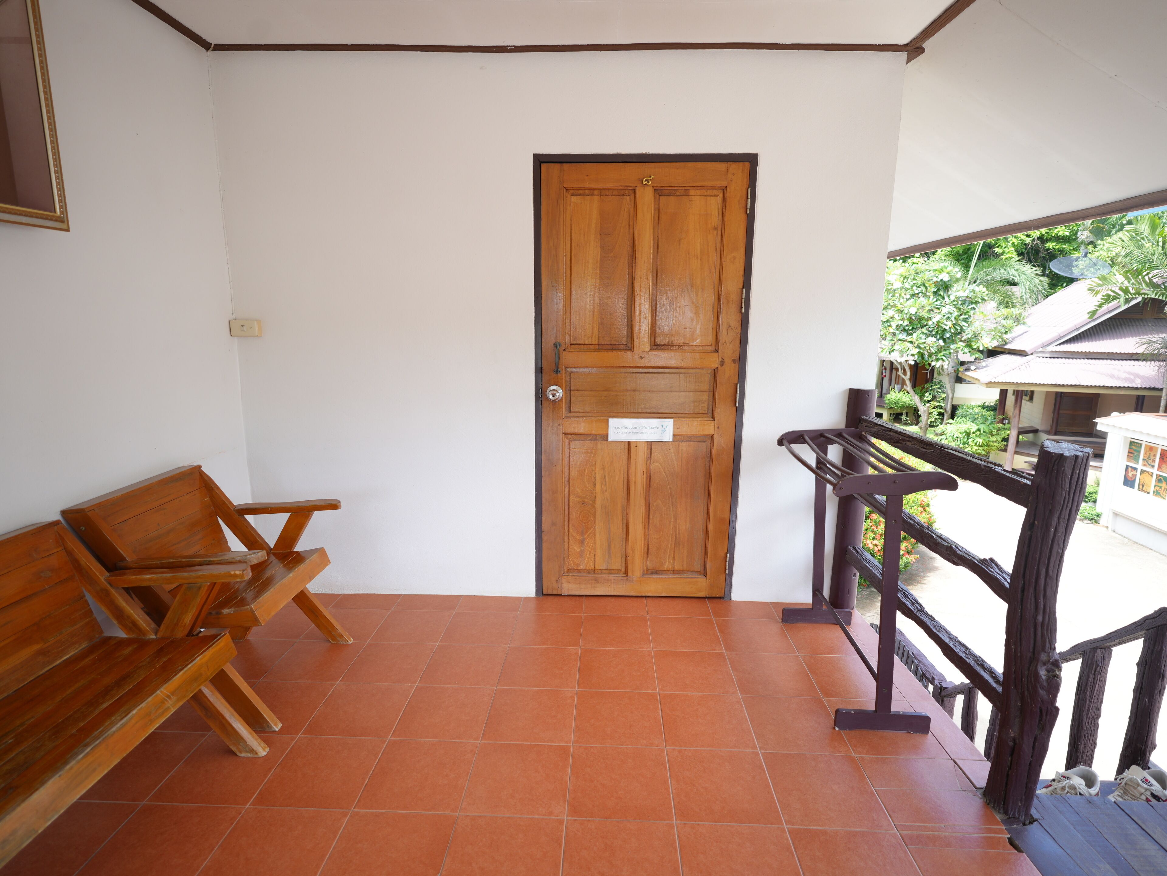 A wooden door with a sign, a wooden bench, and a tiled floor.