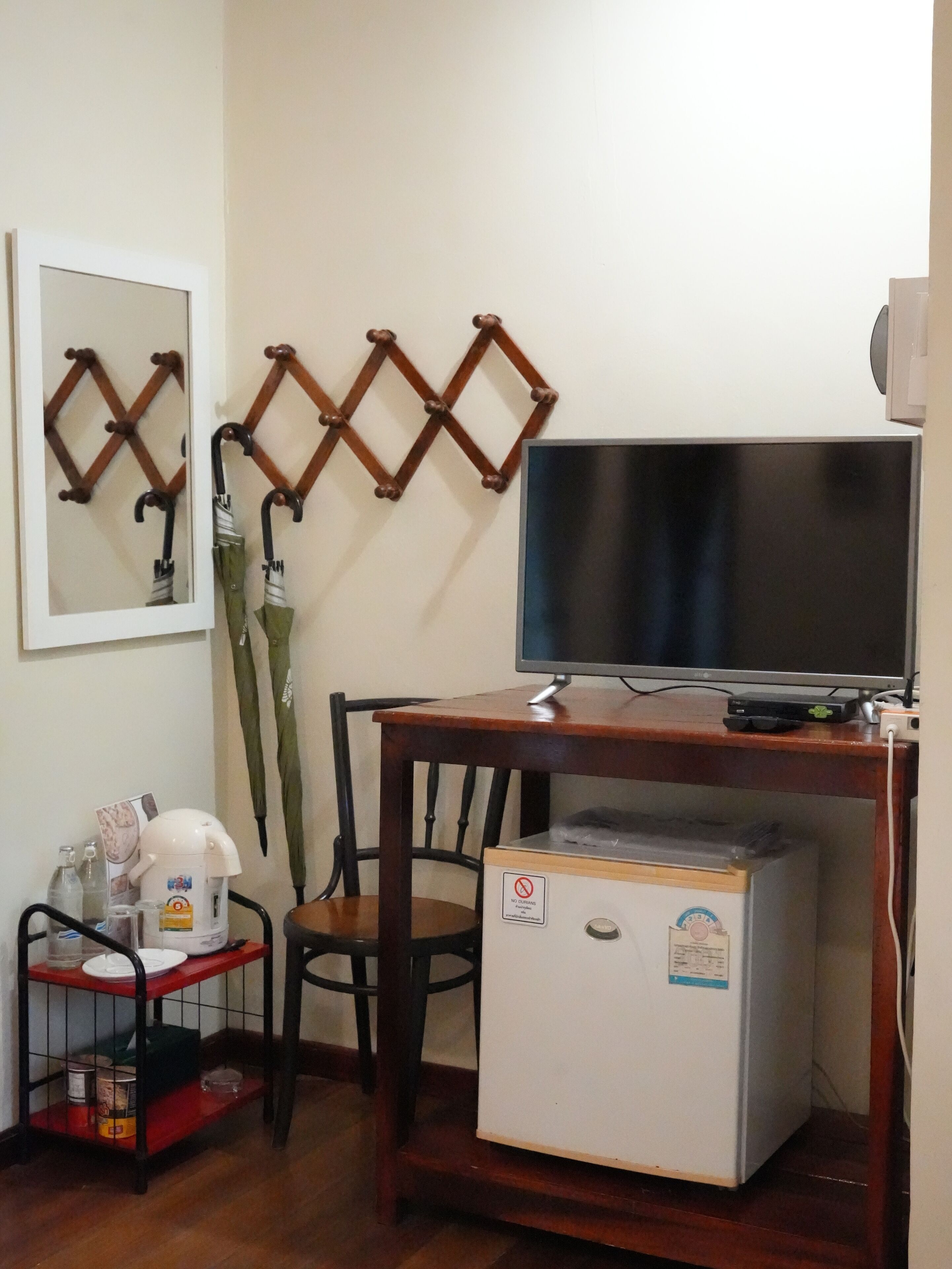 A compact room with a wooden desk, a television, a refrigerator, and a chair.