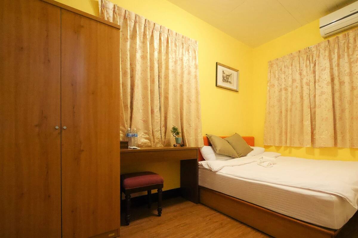 Une chambre à coucher comprenant un lit, un bureau, une chaise et un appareil de climatisation.
