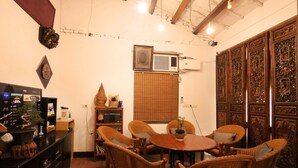 Una habitación con muebles de mimbre, una mesa redonda de madera y una puerta de madera tradicional con intrincados grabados.