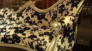 A room with a sofa upholstered in floral fabric, a glass partition, and a traditional Chinese decorative screen. - WE Motel (Kaohsiung)