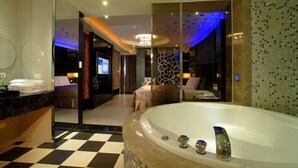 A modern bathroom with a large bathtub, a glass-enclosed shower area, and a checkered floor. - WE Motel (Kaohsiung)