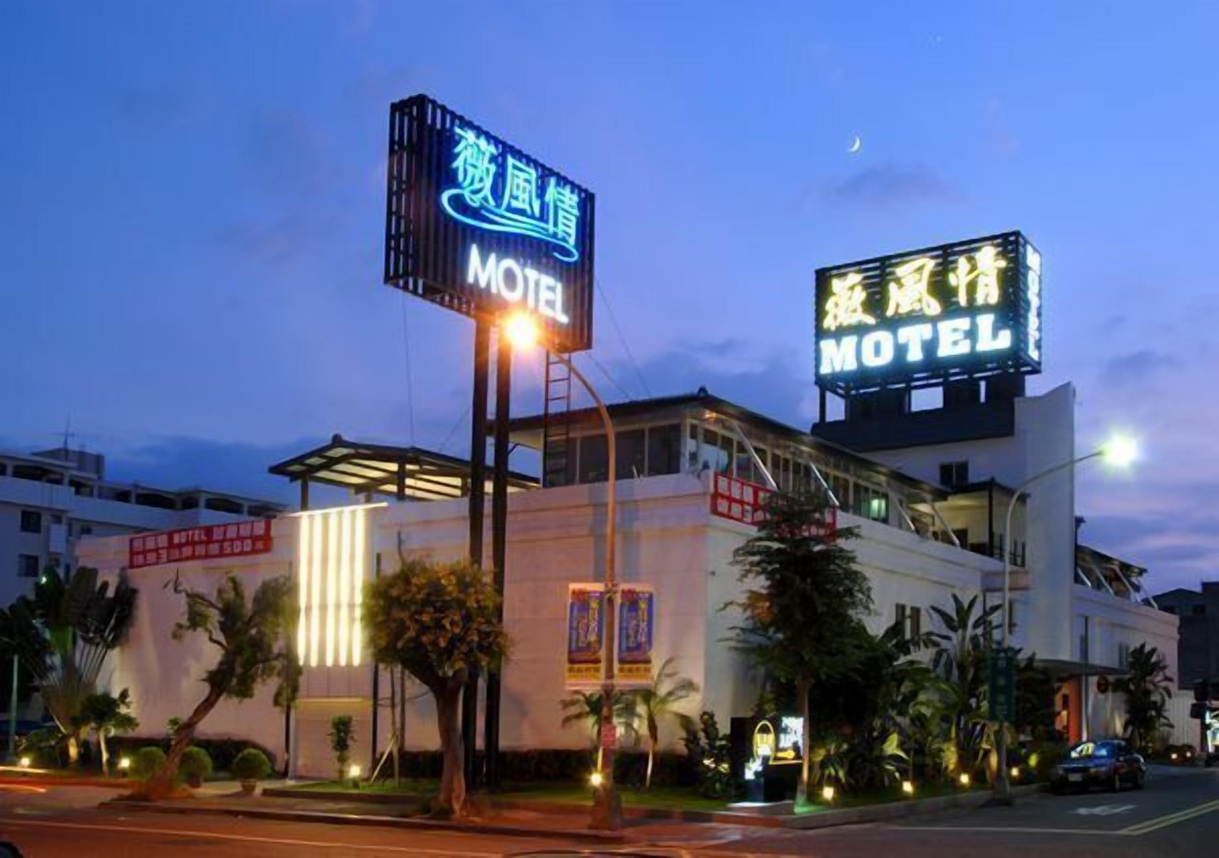 A motel with a prominent neon sign, a modern building facade, and a well-lit entrance area.
