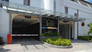A modern building entrance with a glass canopy, a security gate, and a sign indicating the entrance. - WE Motel (Kaohsiung)