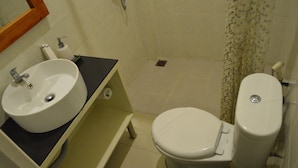 A bathroom with a white sink, toilet, and shower curtain. - Kabana Hotel (Mataram)