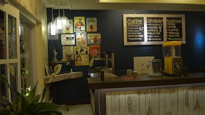 A cozy bar area with a wooden counter, vintage coffee posters, and a coffee machine. - Kabana Hotel (Mataram)