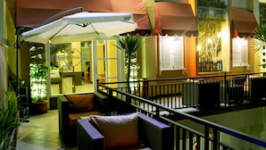 An outdoor seating area with umbrellas, potted plants, and a view of the interior. - Kabana Hotel (Mataram)