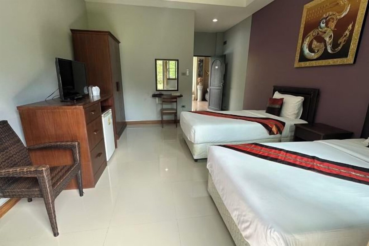 A hotel room with two beds, a desk, a television, and a wardrobe.