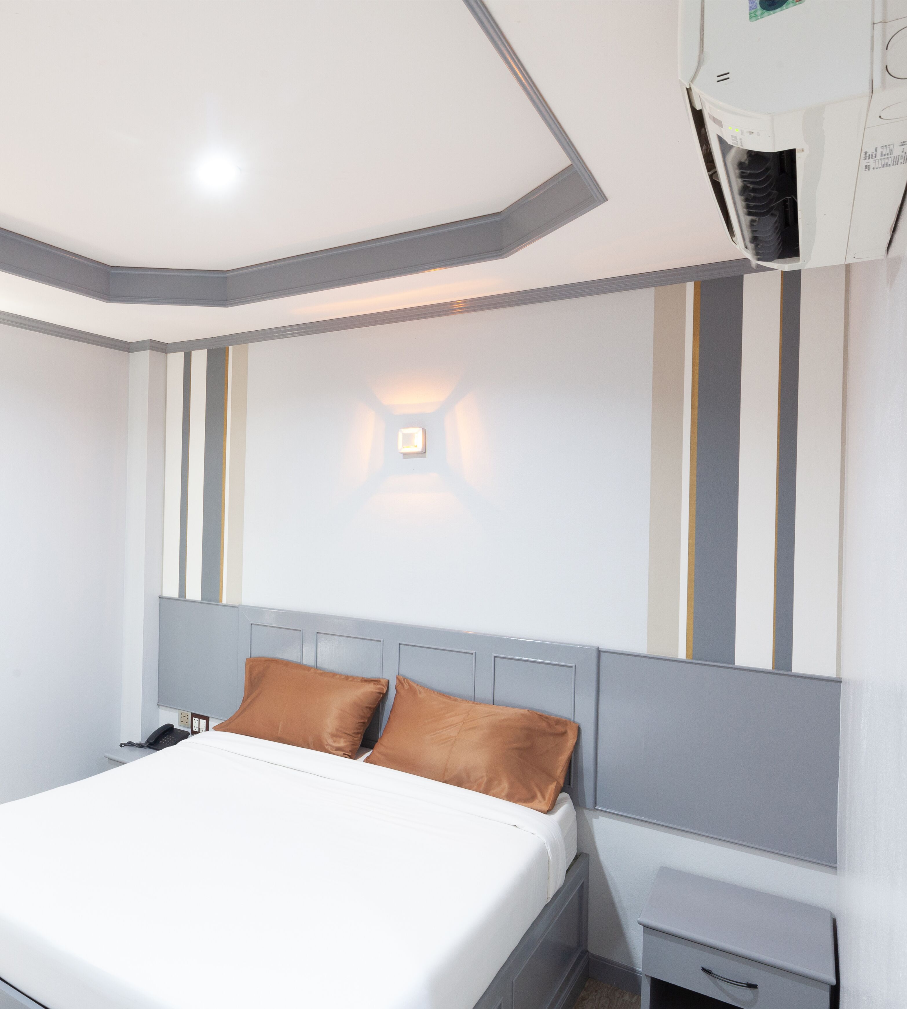 Une chambre d’hôtel équipée d’un lit, d’une table de chevet et d’un climatiseur fixé au mur.