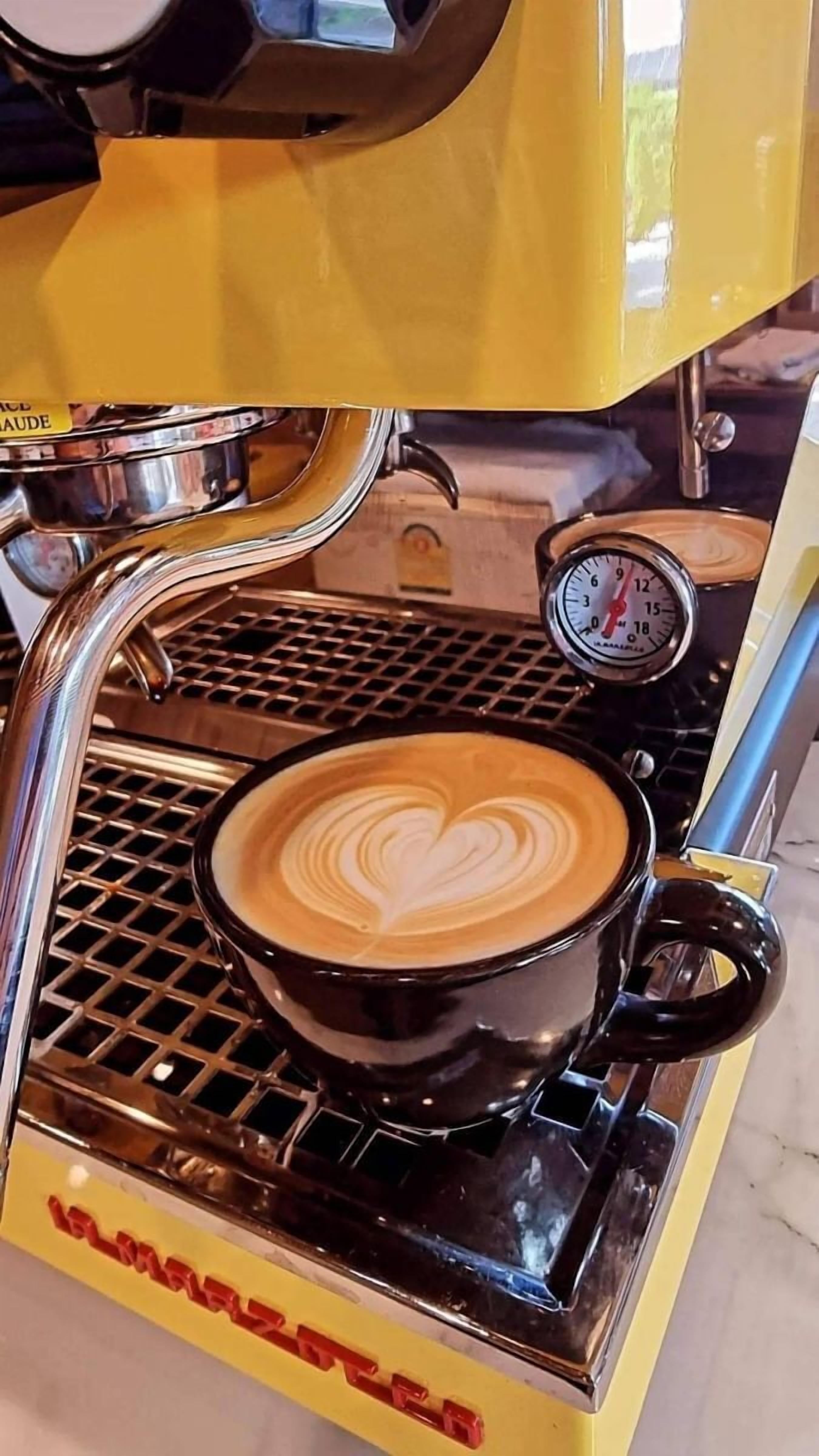 Una cafetera con un arte de latte en forma de corazón en la taza.