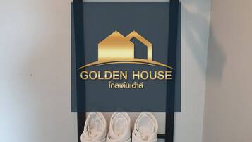 A display of Golden House with a logo, a wooden shoe rack, and three shoes.