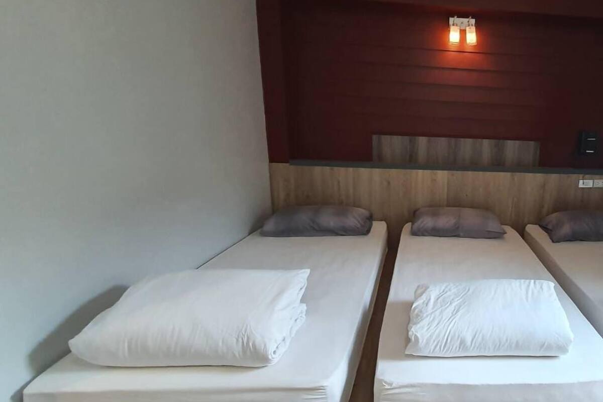 Une chambre avec deux lits simples, chacun équipé d’un oreiller et d’une couverture soigneusement disposée.