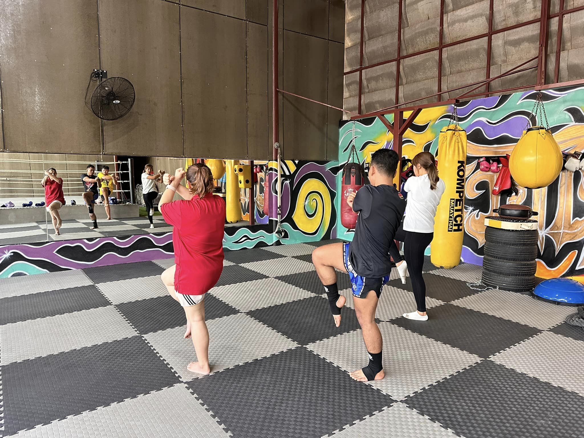 A martial arts training area with mats, punching bags, and a colorful mural.