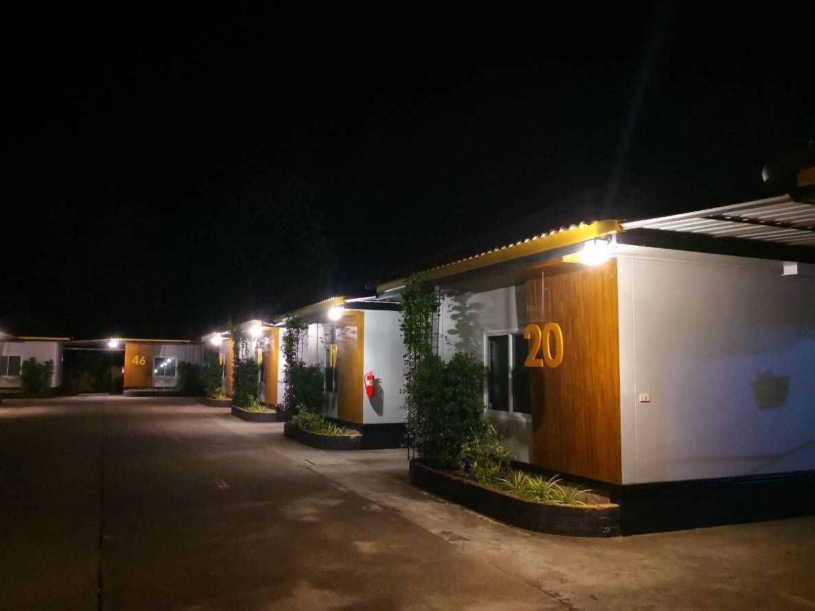 Una hilera de habitaciones de hotel con los números 20 y 46, cada una con fachada de madera y un pequeño jardín.