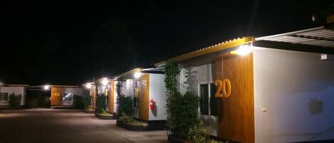 Una hilera de habitaciones de hotel con los números 20 y 46, cada una con fachada de madera y un pequeño jardín.