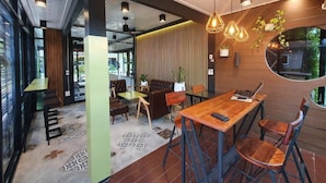 Een modern interieur met een houten eettafel, stoelen en een laptop erop. Er staan potplanten en hangt een spiegel aan de muur.