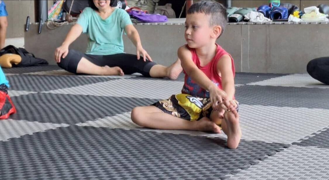 A child sitting on a mat in a room with a checkered floor pattern.