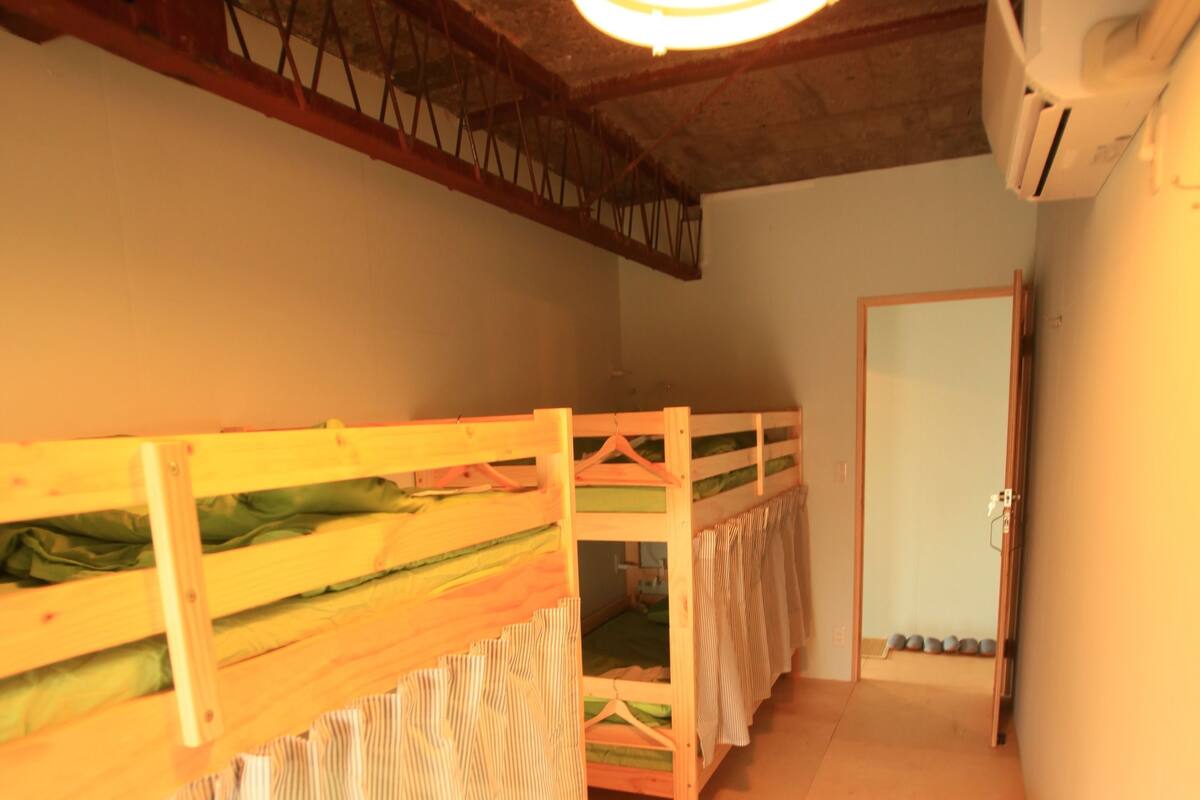 A room with bunk beds, a small table, and a ceiling light.