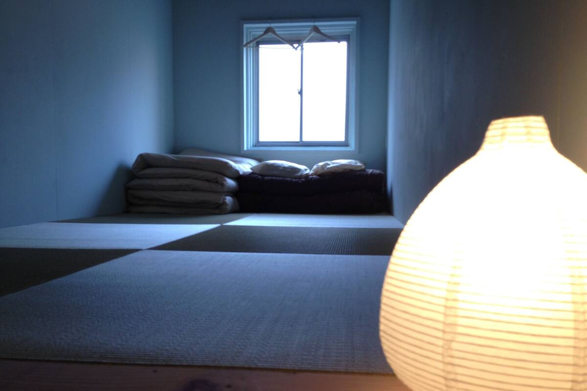 A room with a bed, a window, and a hanging light fixture.