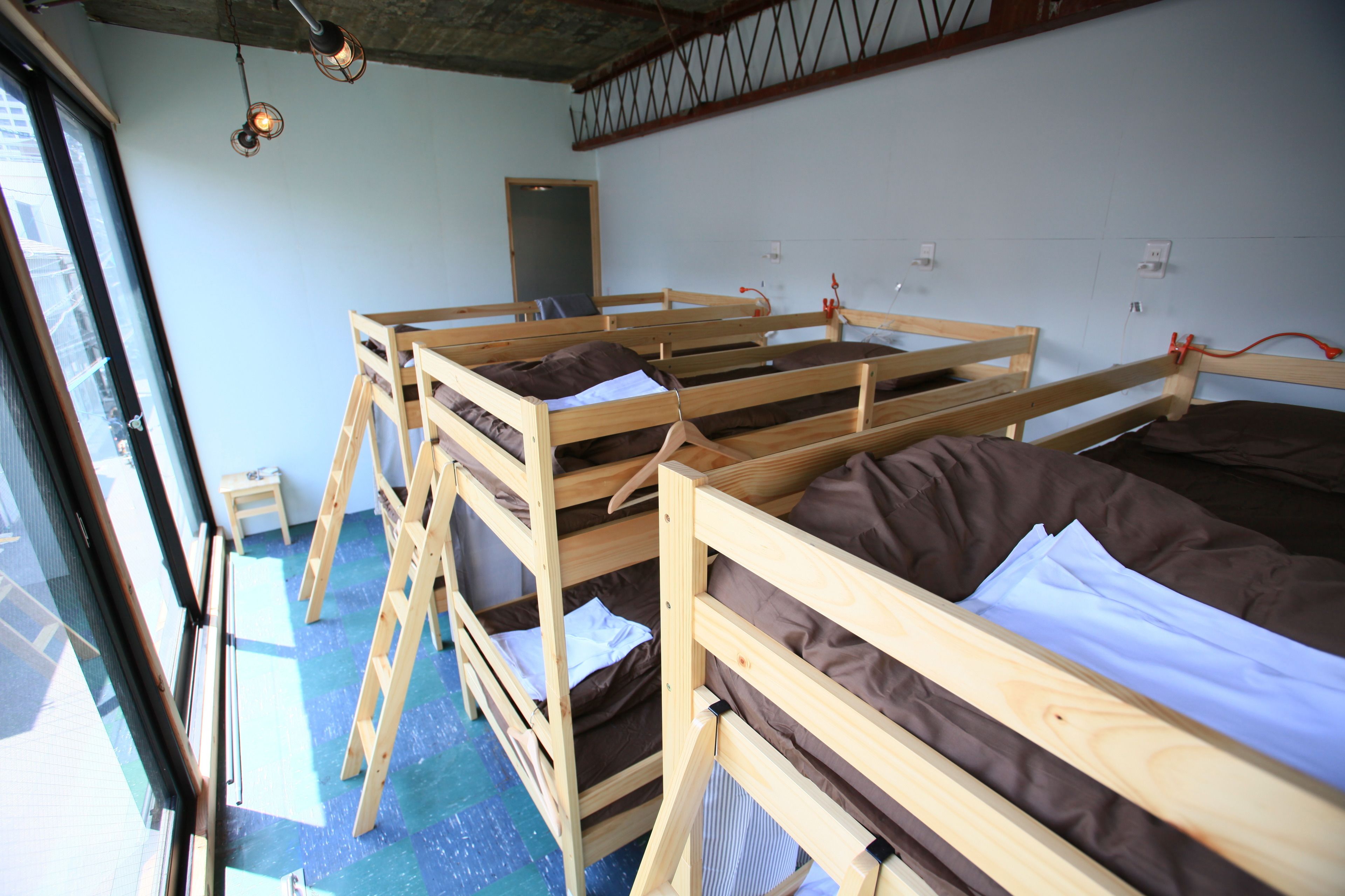A room with bunk beds, a small table, and a window.
