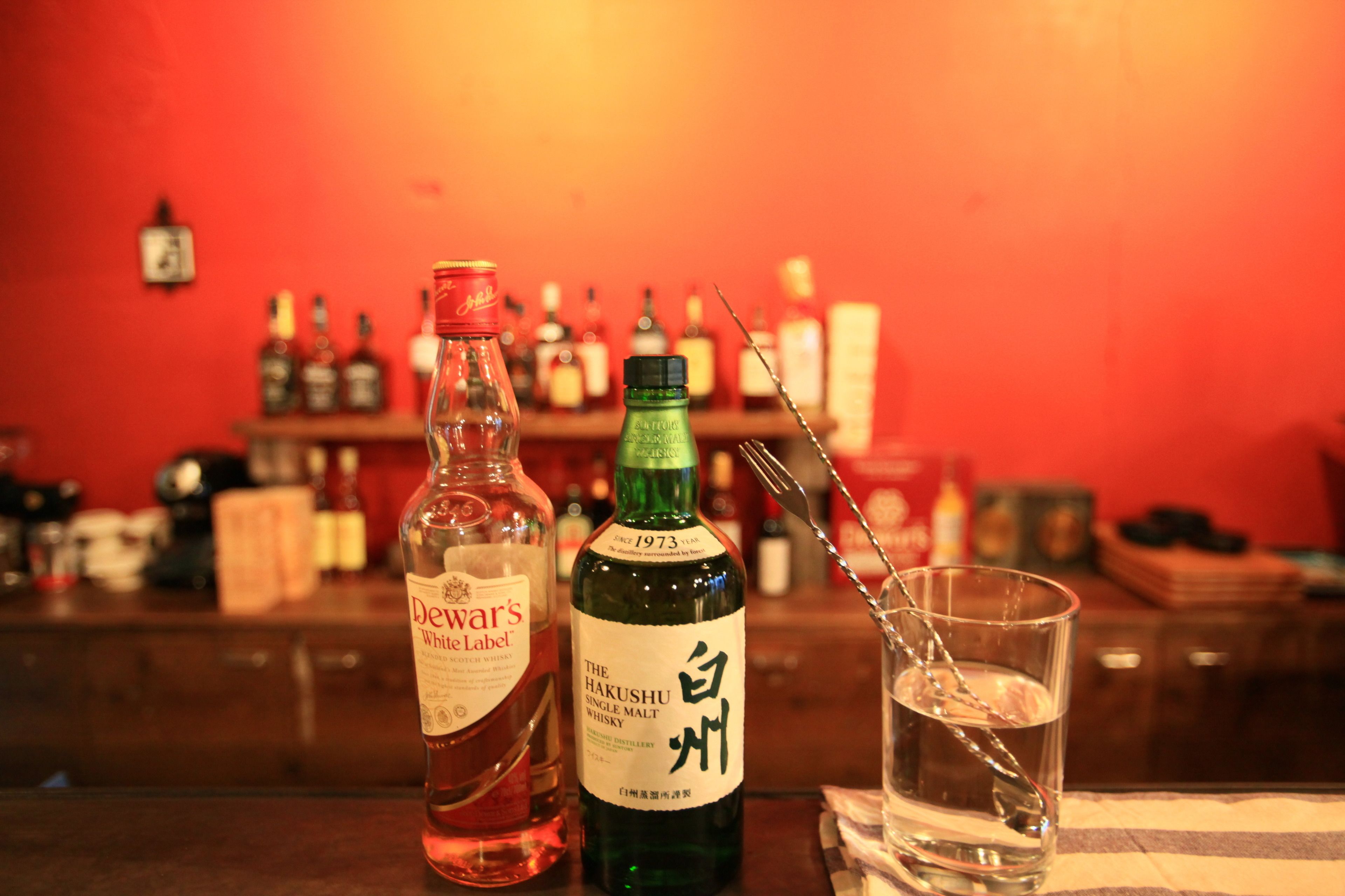 Un bar con botellas de whisky y una copa.