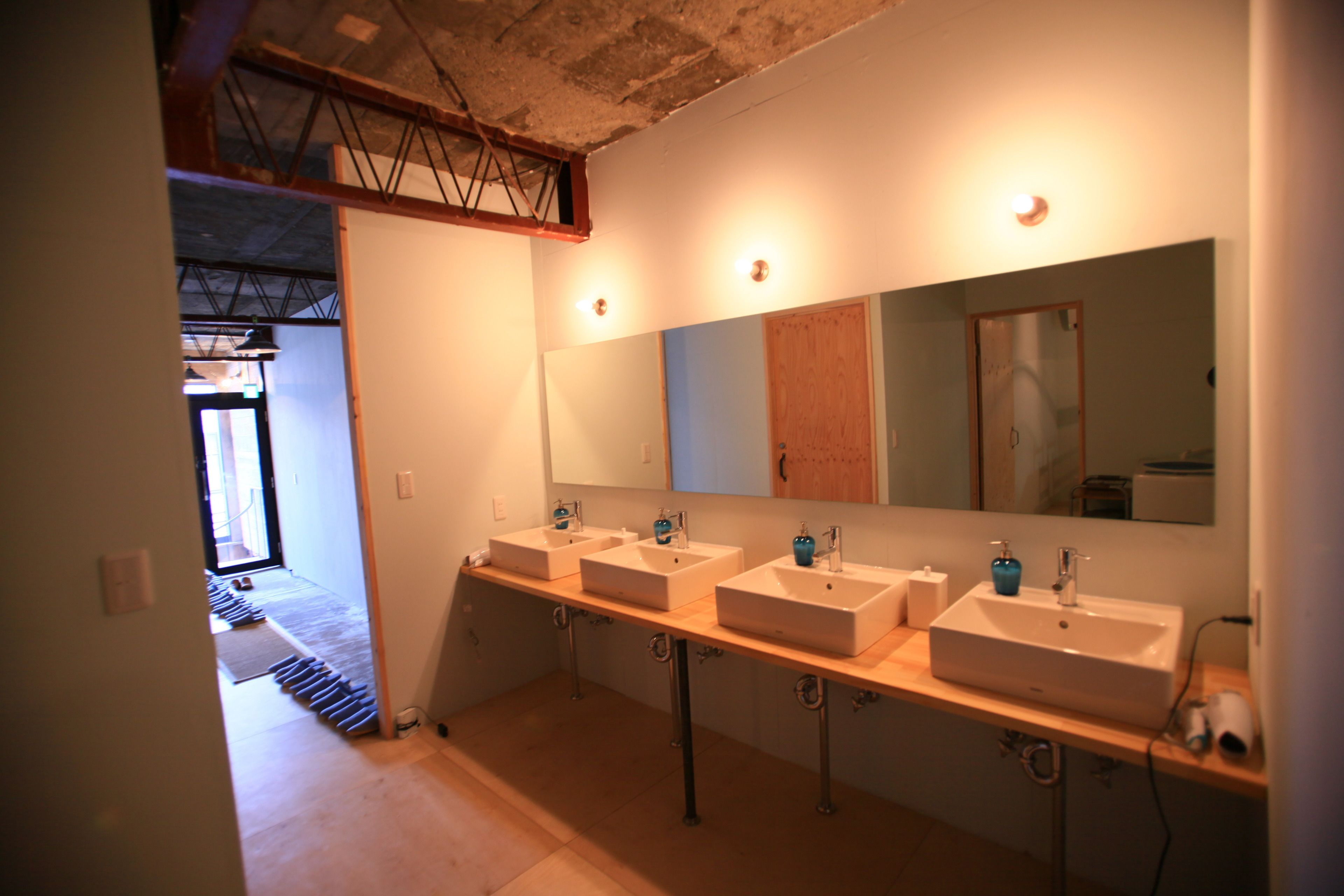 A modern bathroom with three sinks, a large mirror, and a wooden vanity.