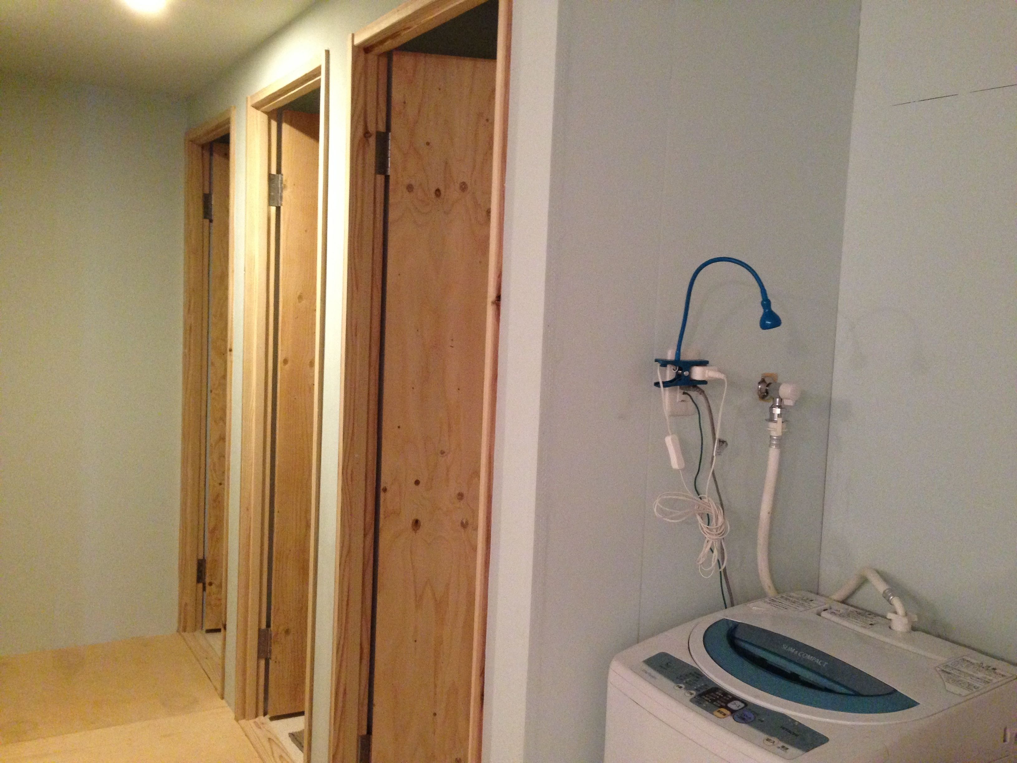 A room with a built-in washer and dryer, wooden doors, and a plain wall.