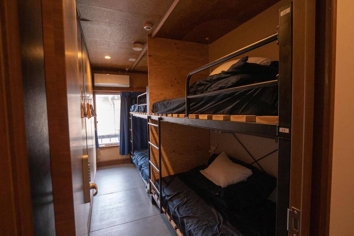 A narrow corridor with bunk beds on one side and a window at the end.